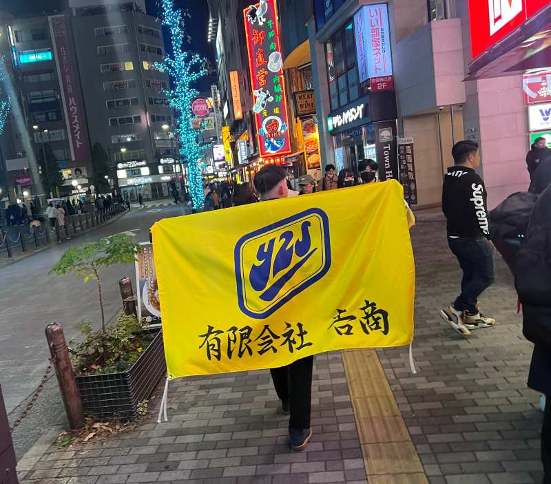 𠮷商の旗を掲げて歩くメンバー